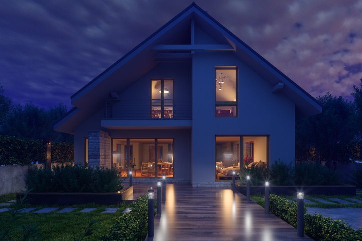 Modern house illuminated warmly at night with a serene pathway.