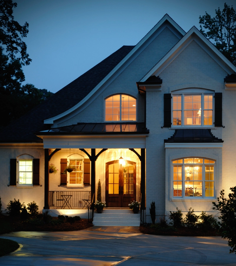 A warmly lit house at dusk with a welcoming porch.