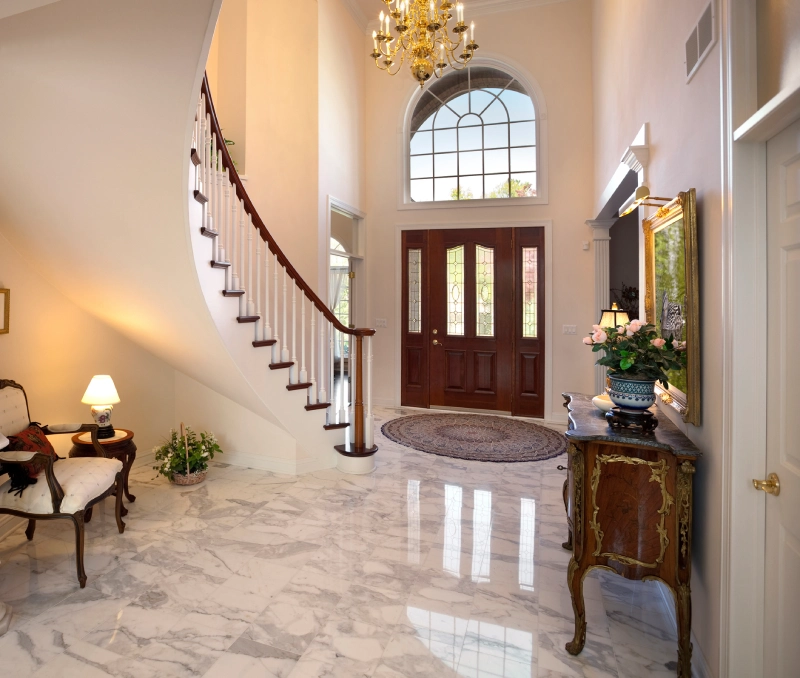 Elegant foyer with marble floors and a curved staircase.